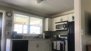 Une cuisine avec des meubles blancs, un four à micro-ondes, un grille-pain et un réfrigérateur.