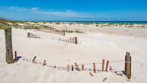 En sandstrand med trästaket och en klarblå himmel.