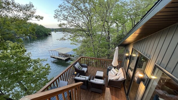 A deck with outdoor seating, a dock, and a river view. - Modern lakeside private home, dock, main channel views, off Horsehoe Bend! (Lake Ozark)