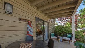 A covered patio with a table, chairs, and a hanging towel. - Salty Siesta: Cozy Condo-Walk to Beach-Pools-Golf! (Miramar Beach)