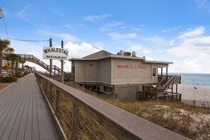 Eine hölzerne Struktur am Strand, mit der Aufschrift 'Whale's Tail', darüber ein Schild für 'Whale's Tail Restaurant'.