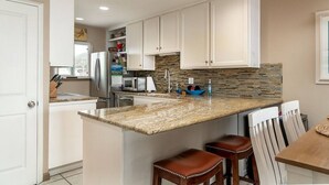 A modern kitchen with white cabinets, granite countertops, and a central island with bar stools.