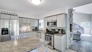 A modern kitchen with granite countertops, stainless steel appliances, and a stone accent wall.