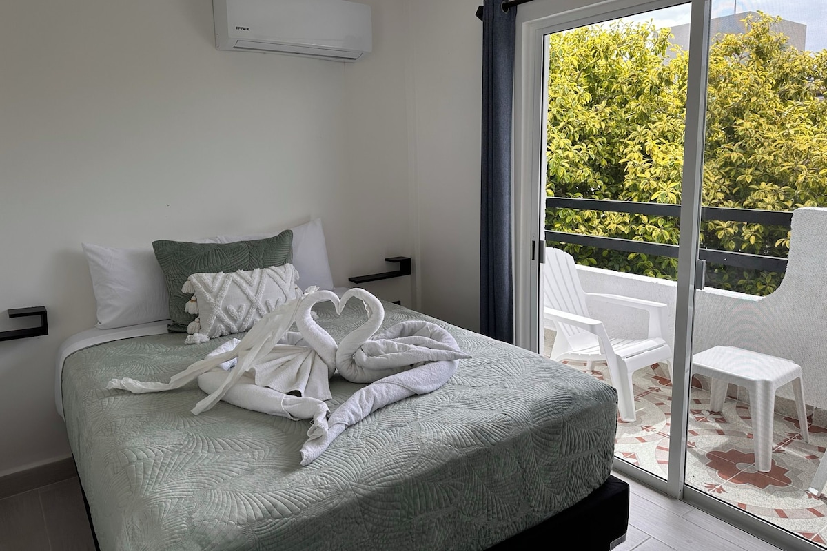 A bedroom with a bed, a window, and a view of greenery outside.