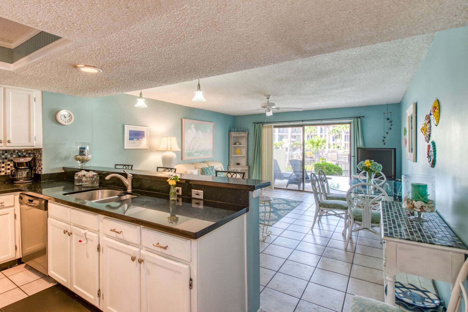 A kitchen with white cabinets, a black countertop, and a dining area with a table and chairs.