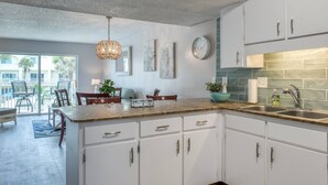 Une cuisine moderne avec des armoires blanches, un comptoir en granit et un luminaire suspendu.