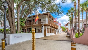 A street view with a building featuring balconies, flags, and a sign for 'St. George Street'. - Bleu Daze Cottage (St. Augustine)