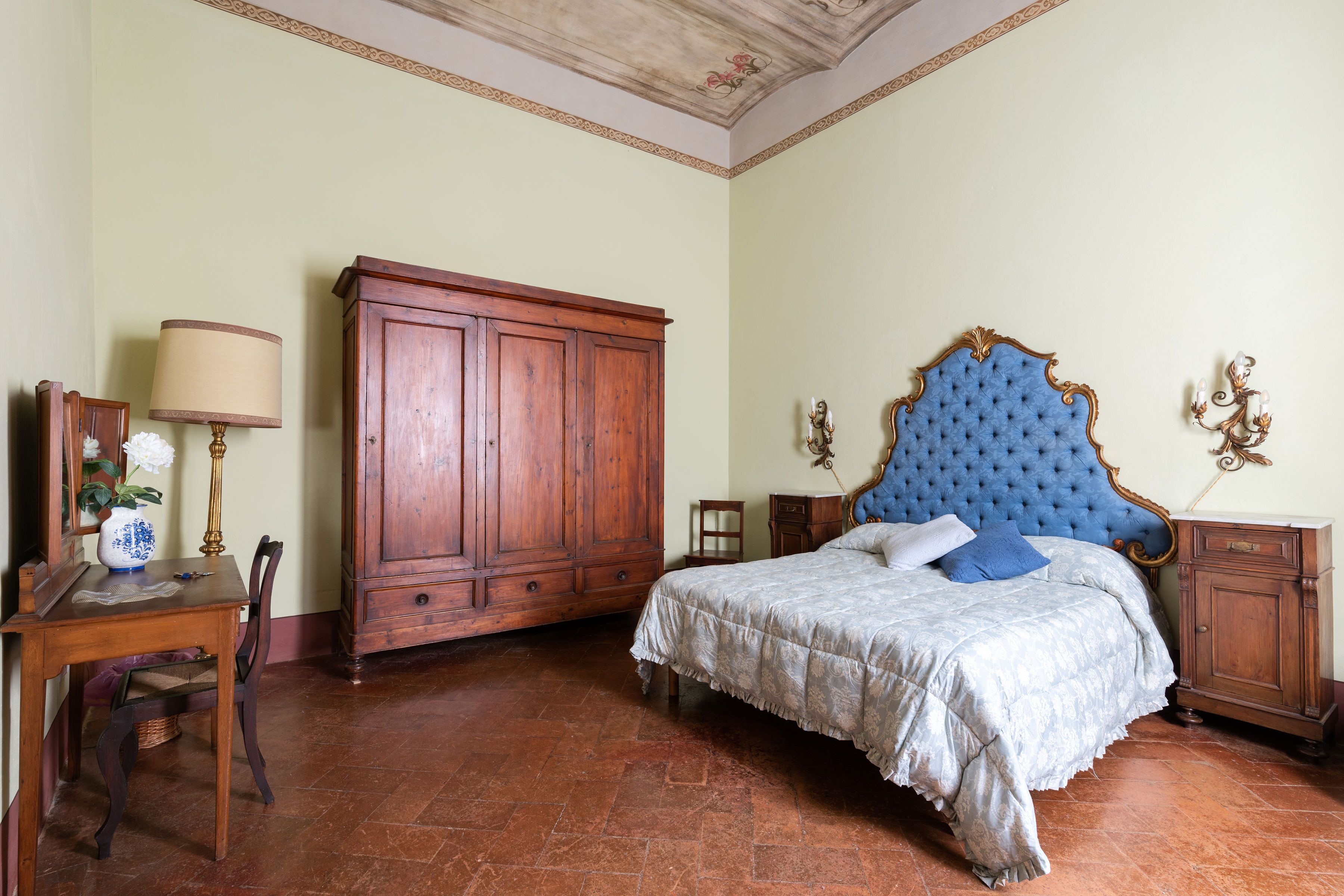 Un dormitorio con una cama grande, un armario de madera y un escritorio con lámpara.