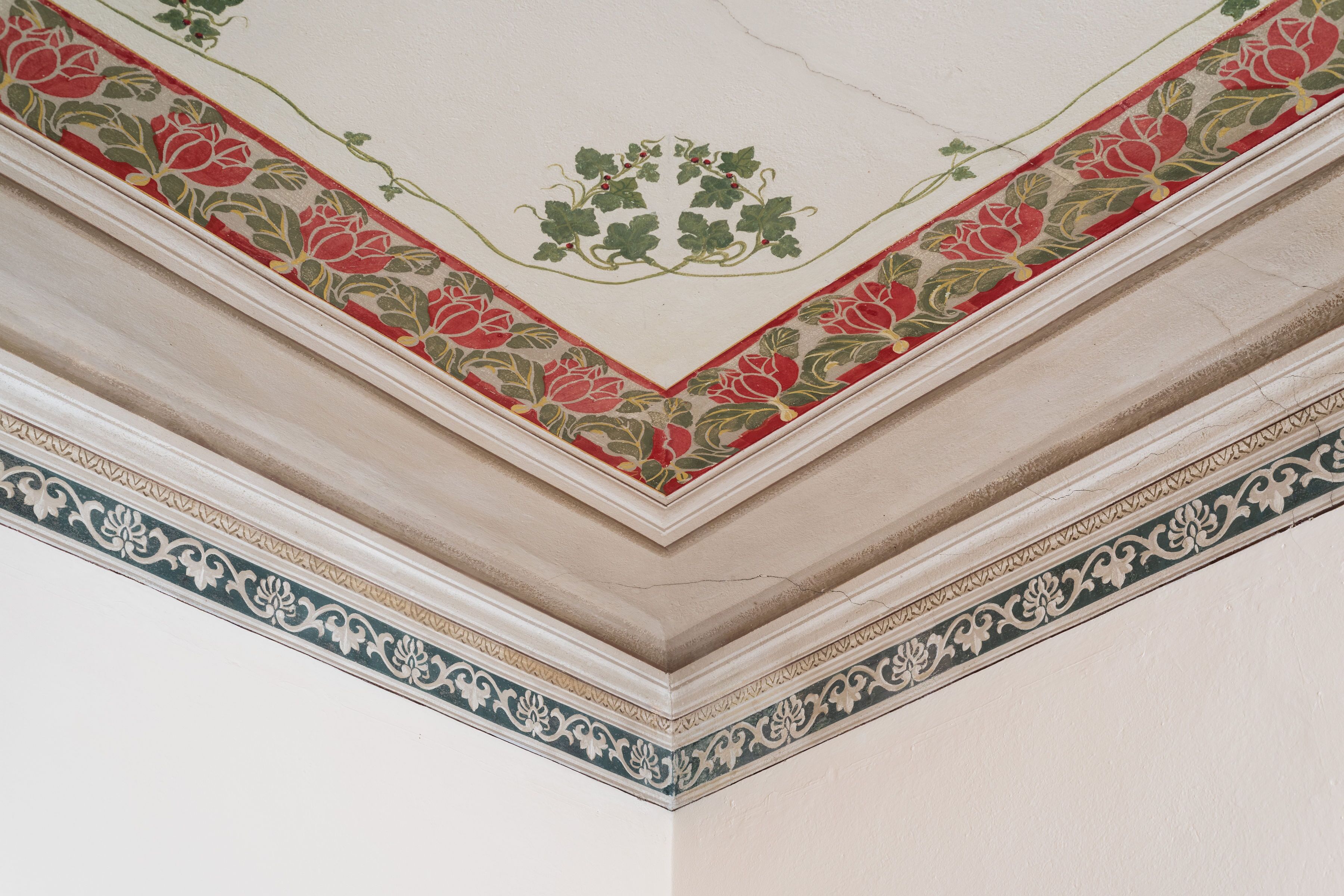 Een plafond met bloemenmotieven en decoratieve sierlijsten.