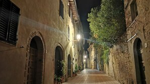 A narrow street with arched doorways and brick buildings at night. - San Gimignano Dependance Rose's Rooms, with 4 rooms, full center, fast WiFi. (San Gimignano)