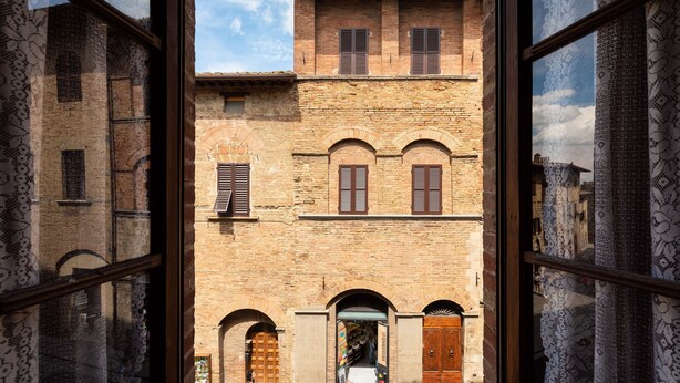 A view of a traditional brick building with arched doorways and wooden shutters. - San Gimignano Dependance Rose's Rooms, with 4 rooms, full center, fast WiFi. (San Gimignano)