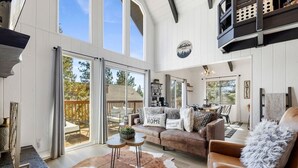 A spacious living room with a large window, a cozy sofa set, and a cowhide rug.