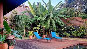 Um deck de madeira com duas espreguiçadeiras azuis e uma piscina pequena.