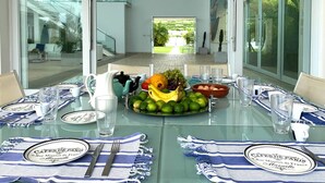 Mesa lista para cuatro personas con una fuente de frutas, vasos y platos de diseño azul y blanco.