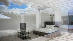 Un dormitorio moderno con una cama, ventilador de techo y una mesa de vidrio con una botella.