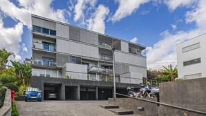 Ein modernes mehrstöckiges Gebäude mit Tiefgarage, einer Treppe und blauem Himmel mit Wolken.