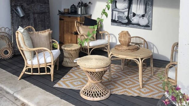 An outdoor seating area with wicker furniture, a woven table, and a large black and white painting on the wall. - Air-conditioned town house with heated swimming pool (Arles)