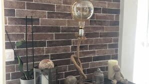 A fireplace mantel with a rustic brick wall, a vintage-style lamp, decorative stones, a small potted plant, and a teddy bear. - Air-conditioned town house with heated swimming pool (Arles)