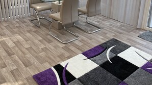 Une salle de réunion moderne, dotée d’une table et de chaises en verre, d’un tapis à motifs et offrant une vue sur l’extérieur grâce à de grandes fenêtres.