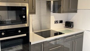Une cuisine moderne équipée d’appareils électroménagers en acier inoxydable, d’un four encastré, d’un four à micro-ondes et d’un grille-pain.