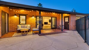 Een modern huis met een bakstenen gevel, een overdekte patio met tuinmeubilair en een zichtbare open haard.