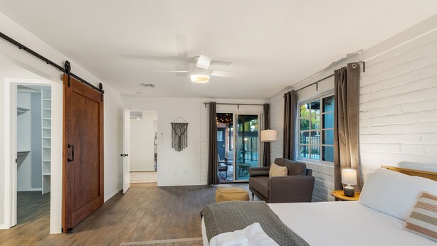 Een hotelkamer met een bed, een bank, een lamp en uitzicht door het raam.