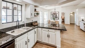 A spacious kitchen with white cabinets, a black countertop, and a large window.