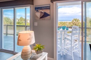 Een balkon met uitzicht op de oceaan, een tafel met stoelen, een lamp en een bloempot.