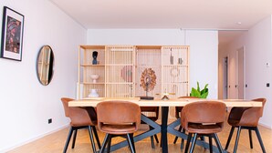 A modern dining area with a wooden table and chairs, a decorative wall piece, and a bookshelf. - R213 - Exquisite City Sanctuary, Brussels (Saint-Josse-ten-Noode)