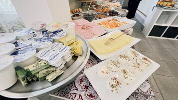 A buffet with various food items including cheese, meats, and pastries.