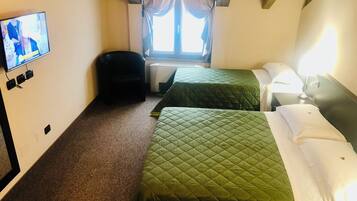 Een hotelkamer met twee bedden, een televisie, een raam met gordijnen en een kleine stoel.