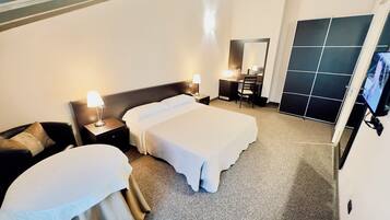 A hotel room with two beds, a desk, a chair, a TV, and a large mirror.