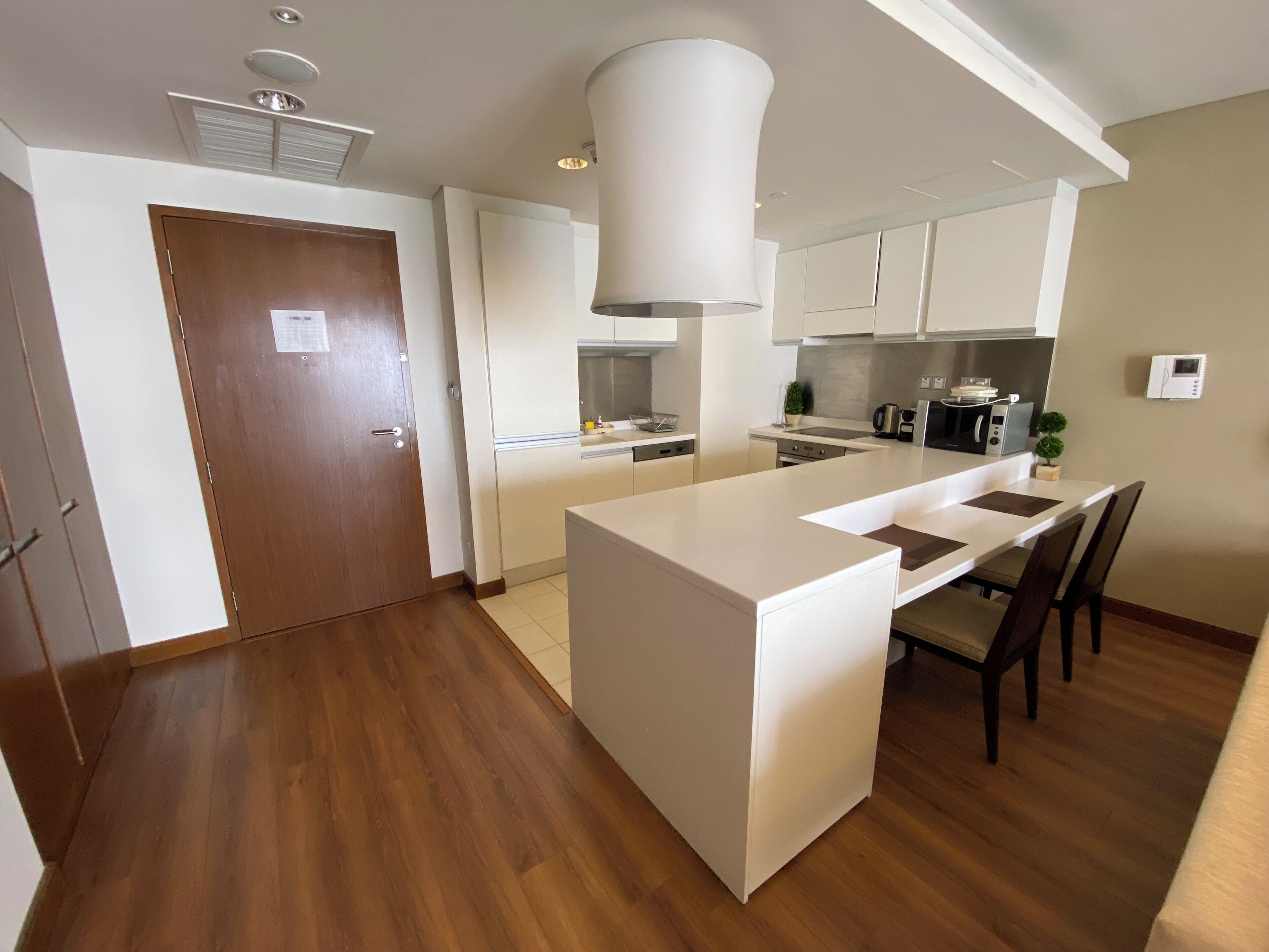 A modern kitchen with white cabinetry, a central island, and a dining area with chairs.