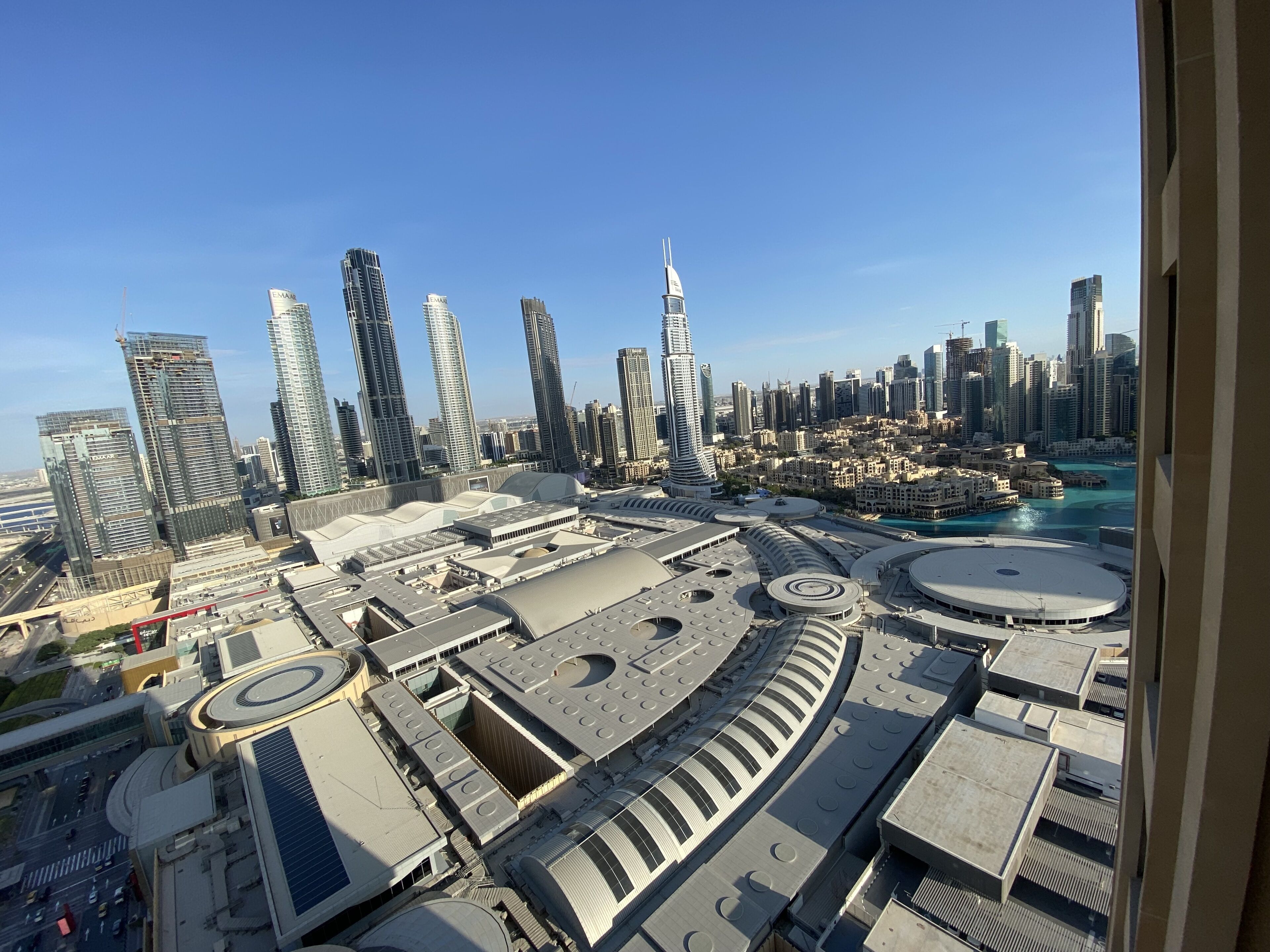 A high-rise building with a distinctive spire, surrounded by other modern skyscrapers and a waterfront.