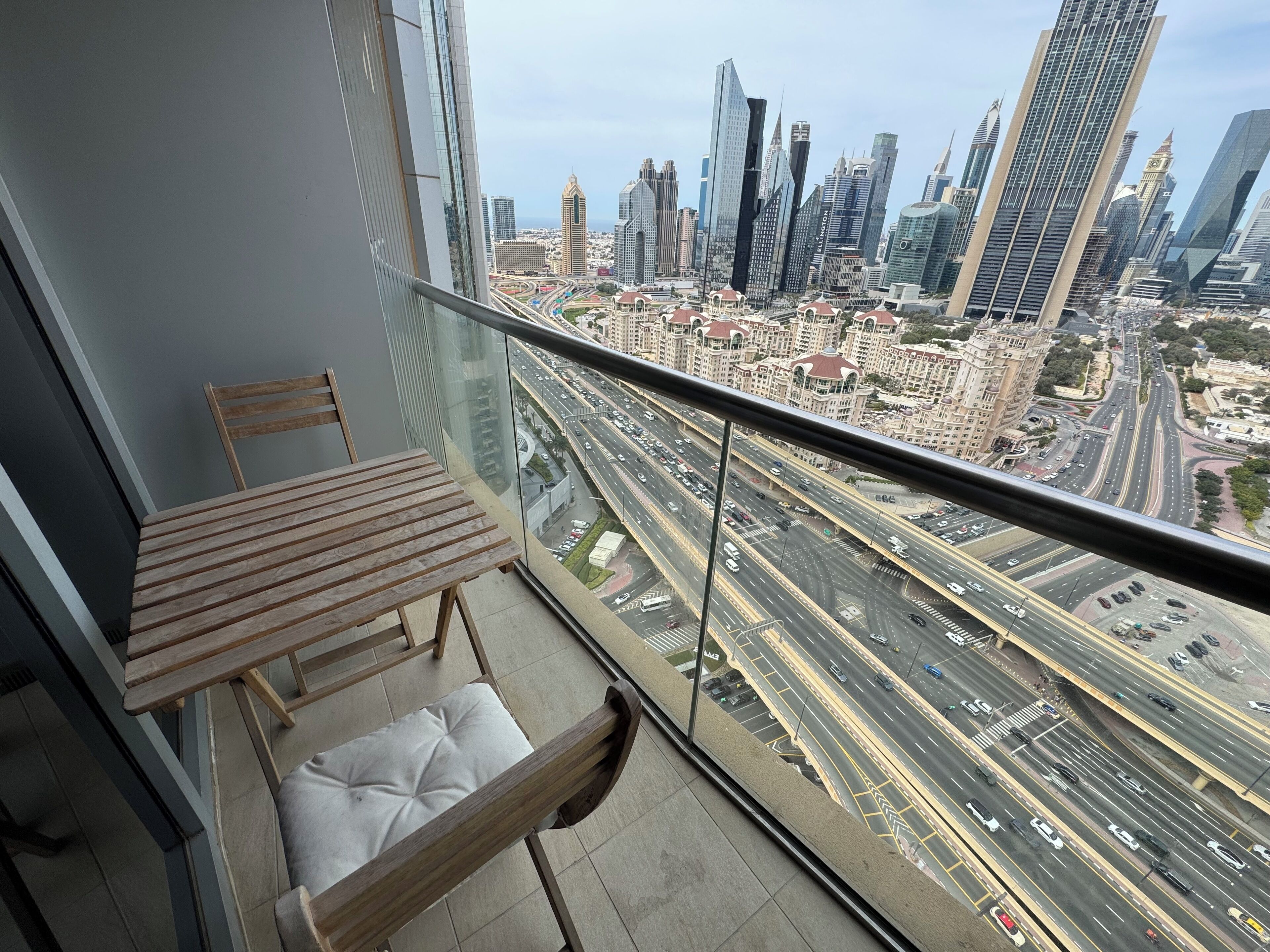 A balcony with a view of a cityscape, including tall buildings and a busy highway.