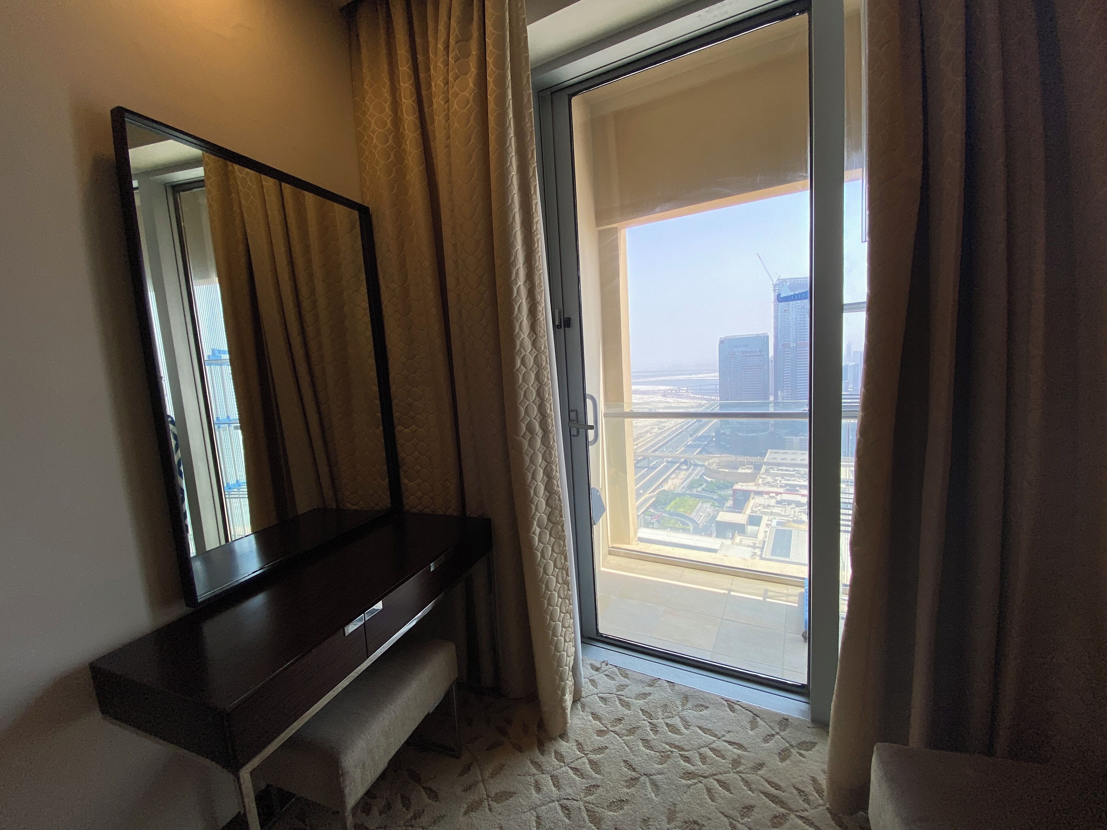 A hotel room with a large sliding glass door leading to a balcony with a city view.