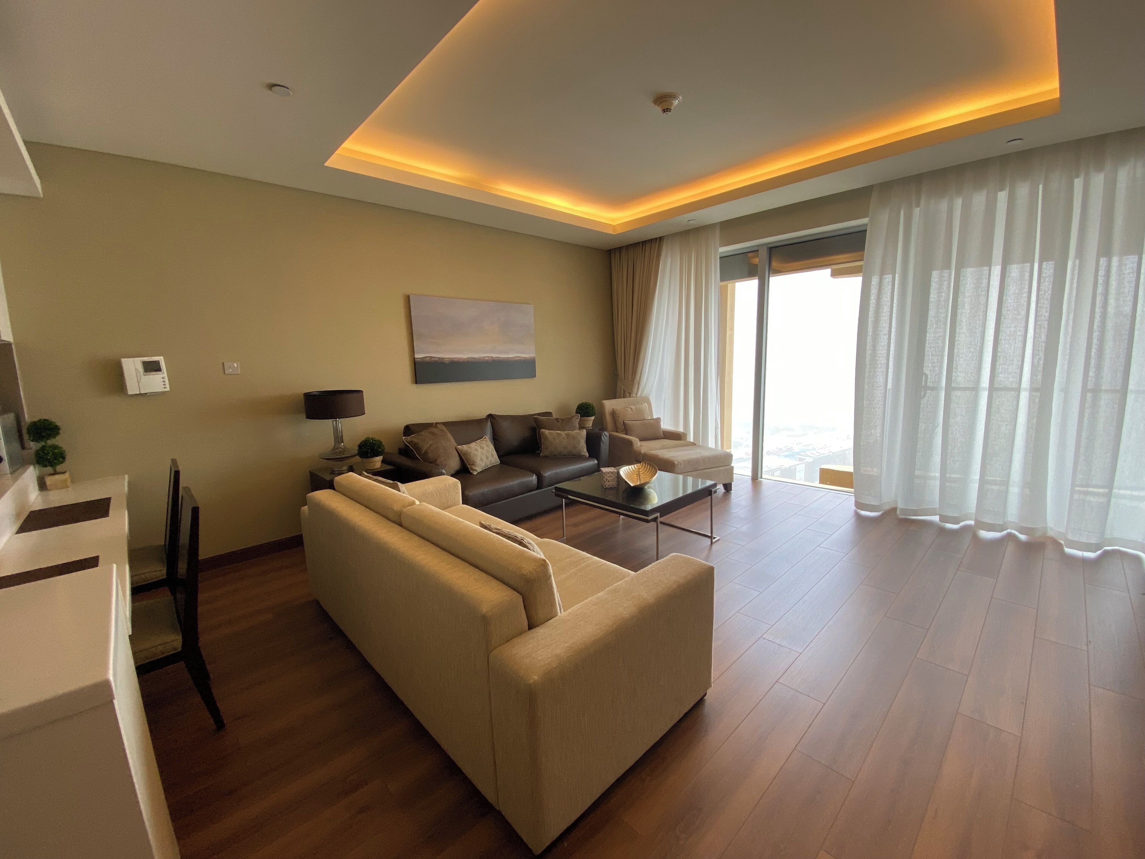 A modern living room with a sofa, a coffee table, and a view of the city through large windows.