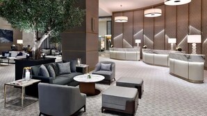 Un hall d’entrée moderne avec un grand arbre, des espaces de détente et un comptoir d’accueil.