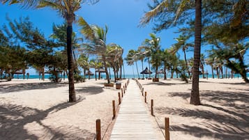 Na praia, areia branca, guarda-sóis