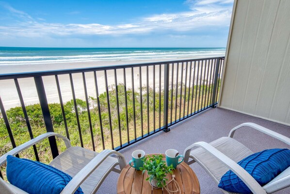 Enjoy the ocean view from this balcony with a round table and two comfortable chairs.