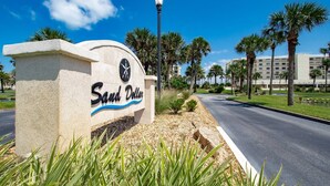 A sign for 'Sand Dollar' with a clear road, palm trees, and a lamp post. - Sand Dollar #205 (St. Augustine)