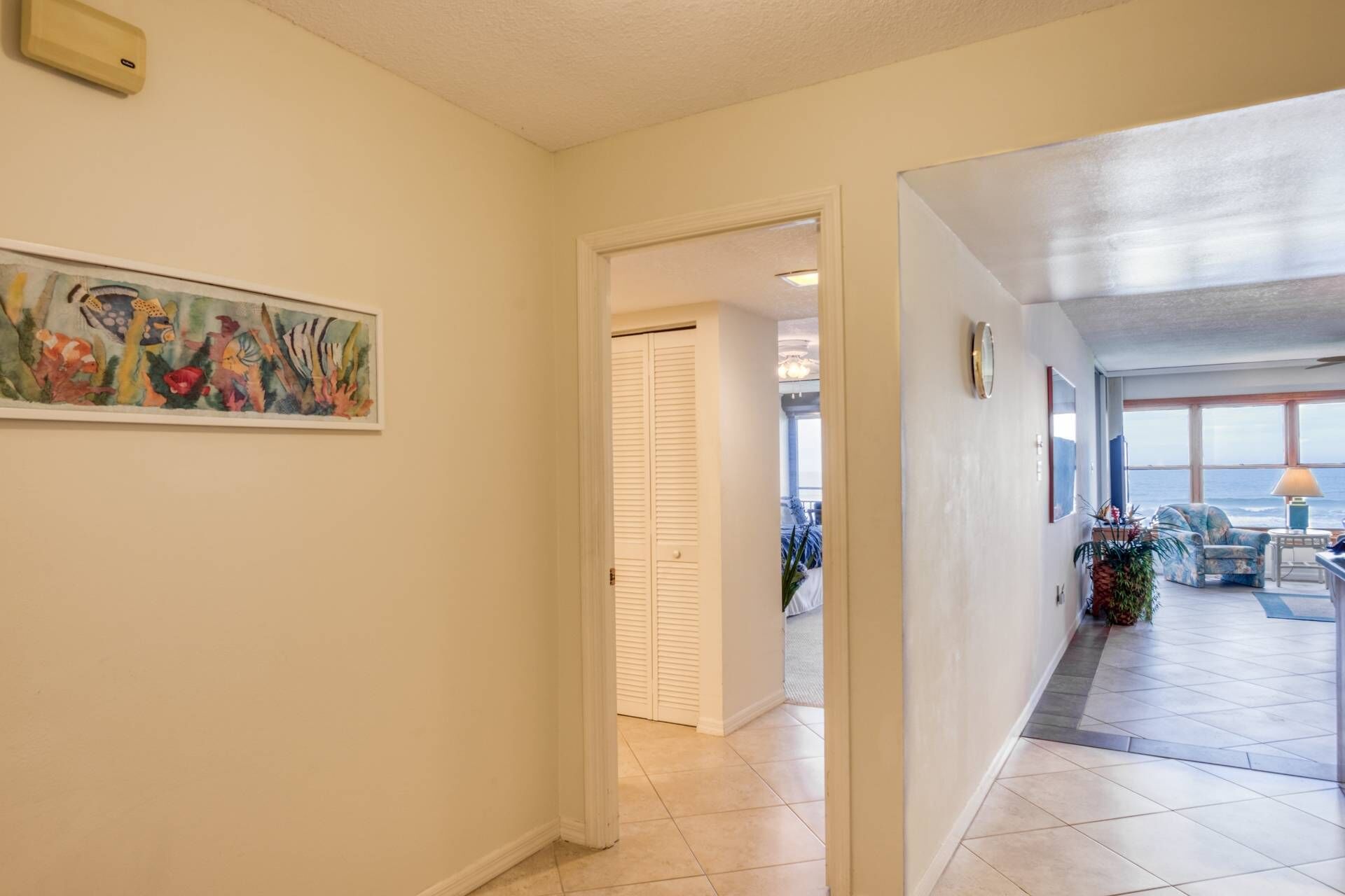 A hallway with a painting, a white door, and a view of a balcony with a table and chairs.