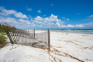 Ein Strand mit Holzlattenzaun und Blick auf den Ozean.