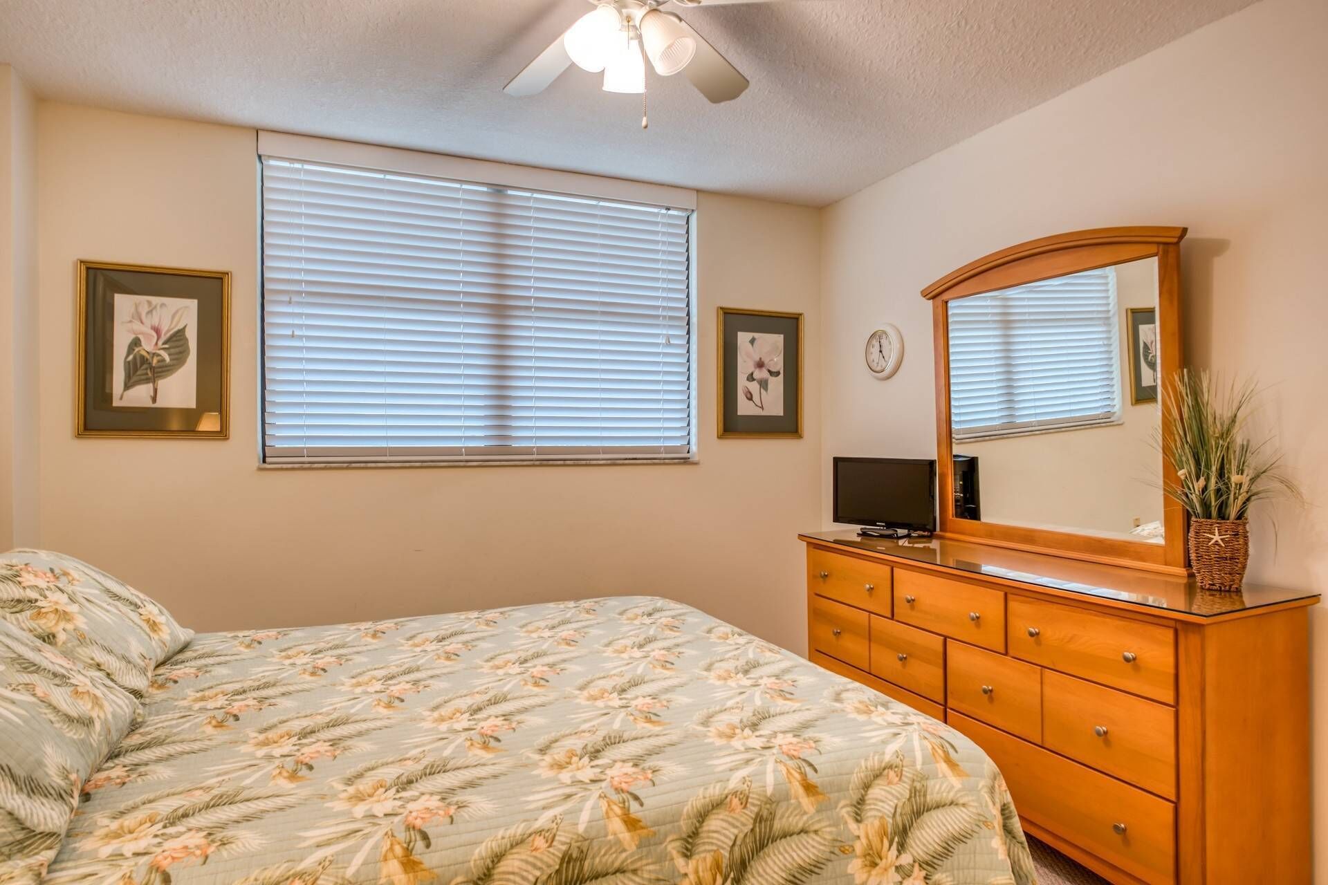 A bedroom with a bed, dresser, and a ceiling fan.