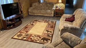 A living room with a large flat-screen TV, a patterned rug, and two sofas. - A Cozy Camp Located 5 Minutes from State Gamelands and a Stocked Trout Stream… (Homer City)