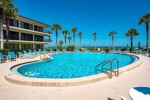 A pool area with a clear blue pool, lounge chairs, and palm trees. - Grandma's Rest East (St. Augustine)