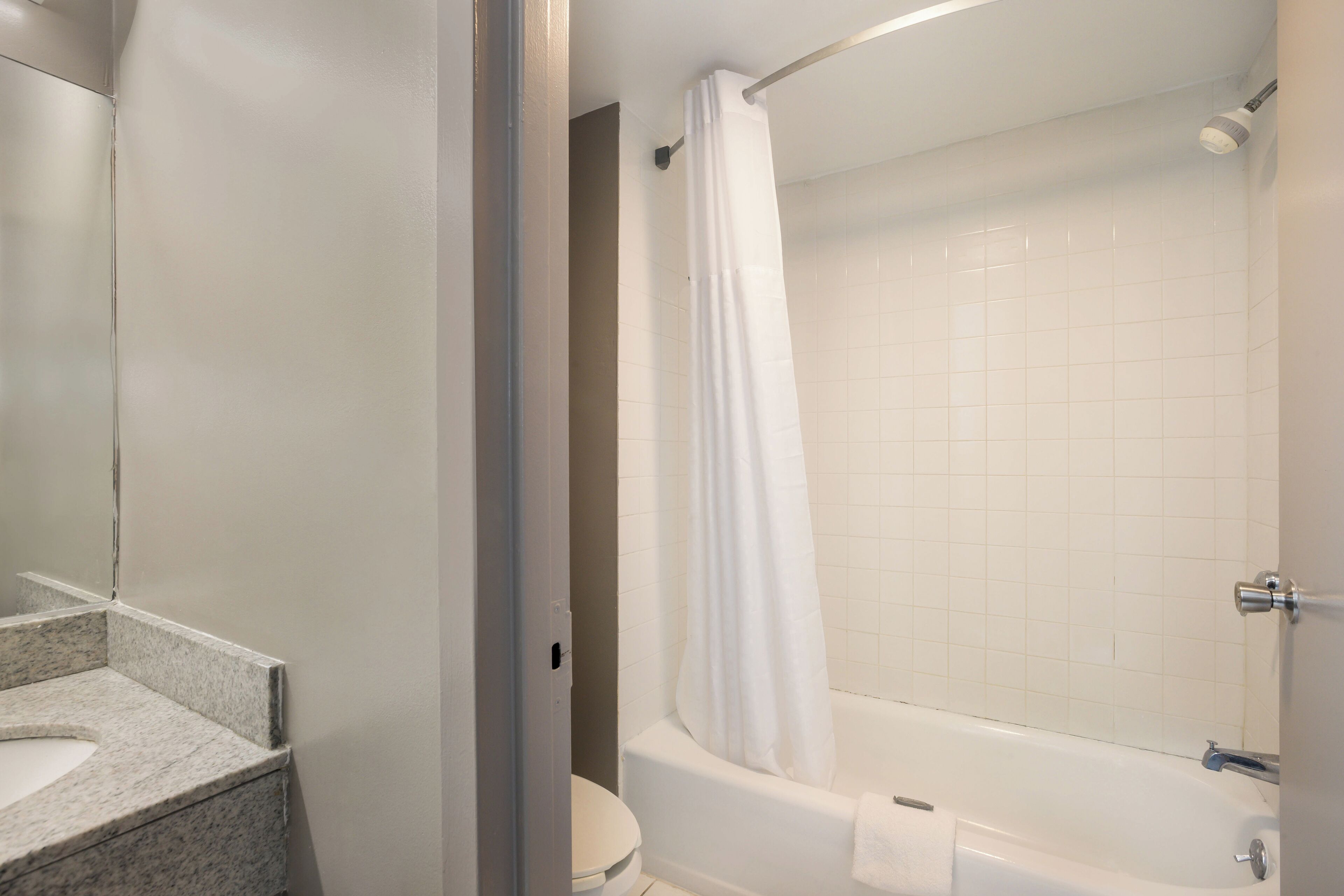 A bathroom with a white bathtub, a shower curtain, and a toilet.