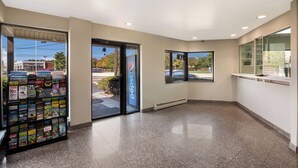 A modern lobby with a magazine rack, glass doors, and large windows. - Red Carpet Inn Edison (Edison)