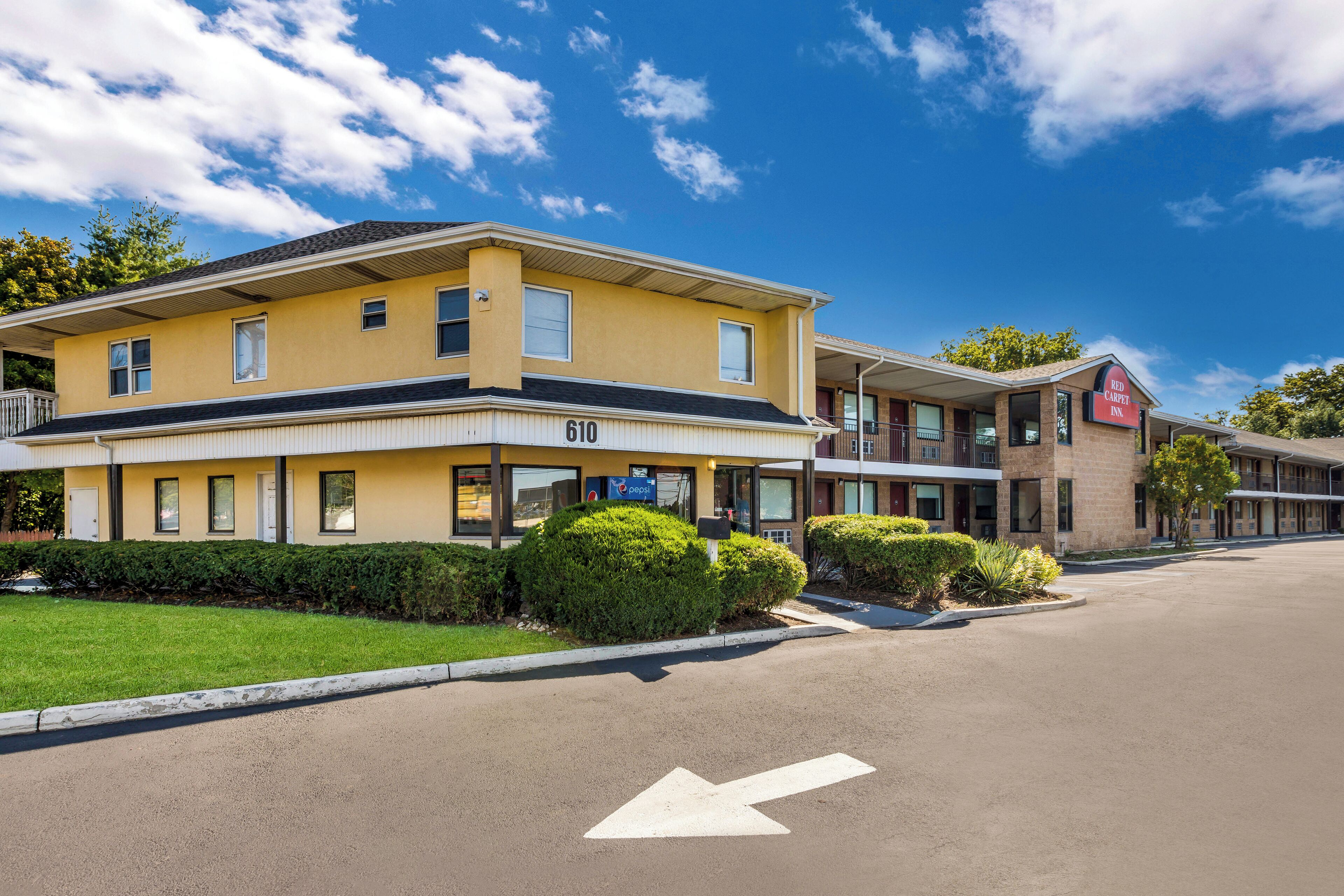 Ein zweistöckiges Hotel mit gelber Fassade, Hausnummer 610, und einem Red Carpet Inn Schild.