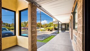 A covered walkway with large windows, a parking lot, and a building with stone walls. - Red Carpet Inn Edison (Edison)